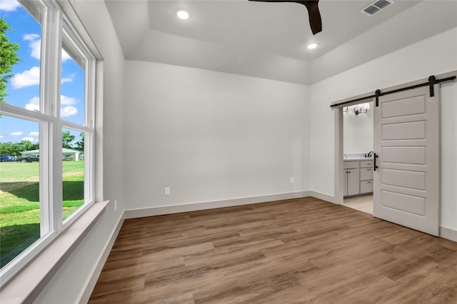 1604 Franklin St, Weatherford, TX 76086 - unfurnished bedroom featuring a barn door, light wood-type flooring, ensuite bath, recessed lighting, and a ceiling fan