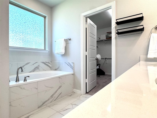 7204 Silent Mill Rd, Arlington, TX 76001 - full bathroom featuring marble look tiles, a garden tub, a walk in closet, and vanity