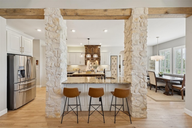 1300 Aberdeen Dr, Lucas, TX 75002 - kitchen with stainless steel fridge, decorative columns, light stone counters, a breakfast bar, and backsplash