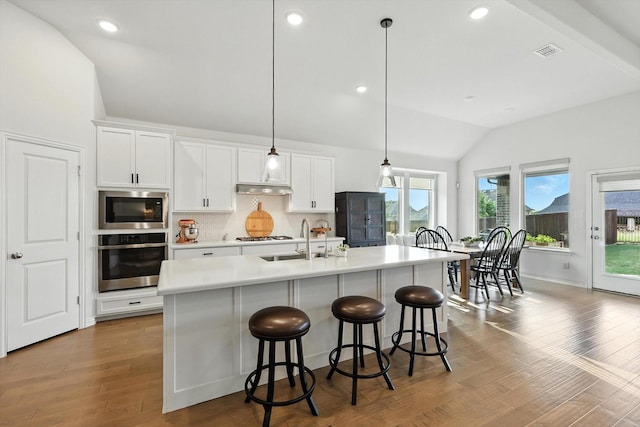 11720 Bull Creek Dr, Northlake, TX 76226 - kitchen with appliances with stainless steel finishes, vaulted ceiling, decorative backsplash, white cabinetry, and a kitchen island with sink