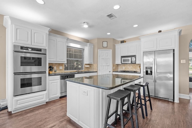 1 Cimarron Ct, Trophy Club, TX 76262 - kitchen featuring appliances with stainless steel finishes, a kitchen island, a kitchen bar, white cabinets, and dark wood finished floors