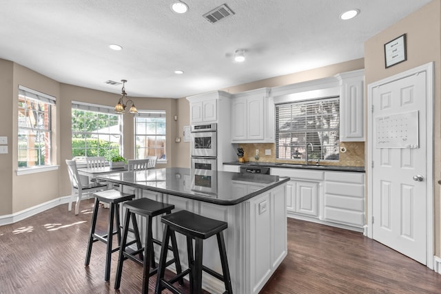 1 Cimarron Ct, Trophy Club, TX 76262 - kitchen with double oven, dark countertops, white cabinets, a center island, and recessed lighting