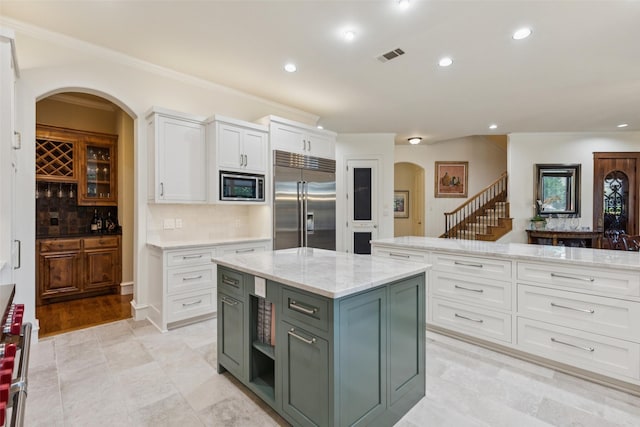 1801 Kinsale Dr, Keller, TX 76262 - kitchen featuring built in appliances, arched walkways, white cabinetry, a kitchen island, and tasteful backsplash