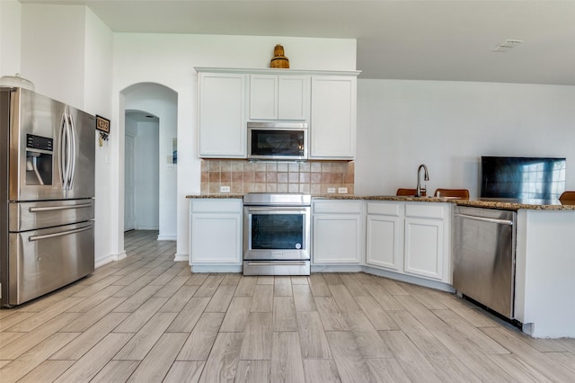 1015 Seider Ln, Grand Prairie, TX 75052 - kitchen featuring stainless steel appliances, light wood-type flooring, tasteful backsplash, and stone counters