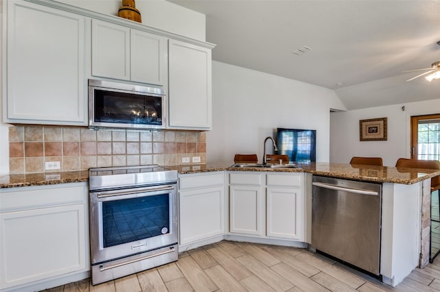 1015 Seider Ln, Grand Prairie, TX 75052 - kitchen with appliances with stainless steel finishes, tasteful backsplash, a peninsula, dark stone counters, and white cabinetry