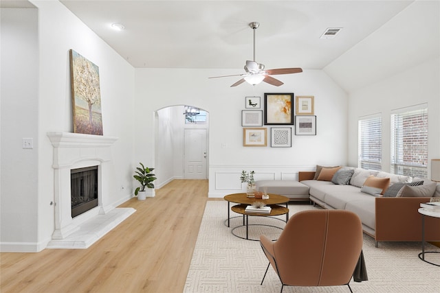 7064 Dreammaker Way, Frisco, TX 75035 - living area with light wood-style flooring, arched walkways, ceiling fan, lofted ceiling, and a fireplace with raised hearth