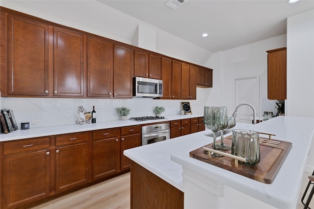 7064 Dreammaker Way, Frisco, TX 75035 - kitchen featuring appliances with stainless steel finishes, recessed lighting, a peninsula, light wood finished floors, and decorative backsplash