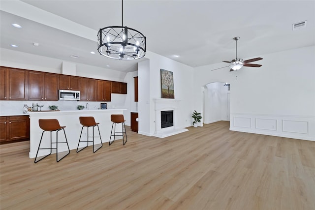 7064 Dreammaker Way, Frisco, TX 75035 - kitchen with stainless steel microwave, open floor plan, arched walkways, a ceiling fan, and recessed lighting