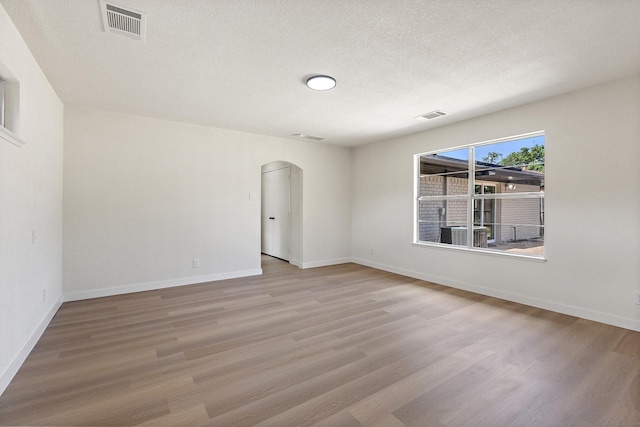 719 Sara Dr, Mesquite, TX 75149 - unfurnished room with arched walkways, light wood-type flooring, and a textured ceiling
