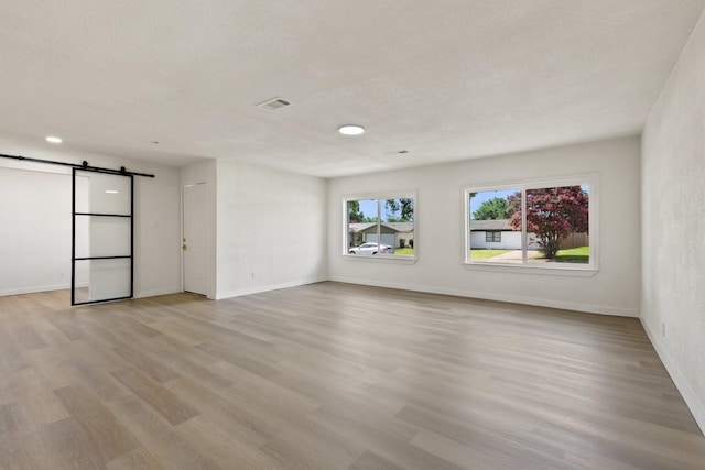719 Sara Dr, Mesquite, TX 75149 - unfurnished room with a barn door, light wood finished floors, and a textured ceiling