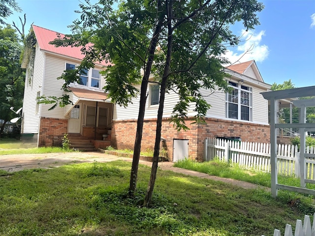 1915 N Jackson St, Palestine, TX 75803 - view of property hidden behind natural elements with brick siding, entry steps, and a metal roof