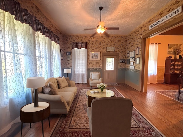 1915 N Jackson St, Palestine, TX 75803 - living room featuring wallpapered walls, wood finished floors, wainscoting, a ceiling fan, and crown molding