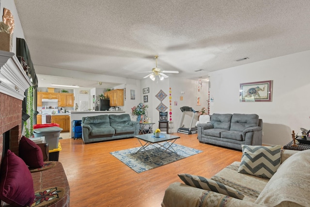 808 Elbe Dr, Arlington, TX 76001 - living room featuring light wood finished floors, ceiling fan, a textured ceiling, and a fireplace
