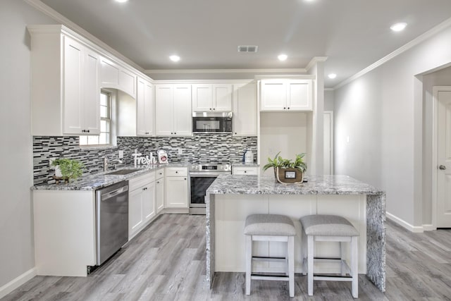 205 John Fielder, Sherman, TX 75092 - kitchen featuring appliances with stainless steel finishes, ornamental molding, decorative backsplash, light wood-type flooring, and white cabinetry