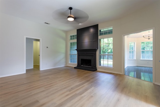 1526 Shadow Run, Weatherford, TX 76086 - unfurnished living room featuring a ceiling fan, light wood-type flooring, a brick fireplace, and a chandelier
