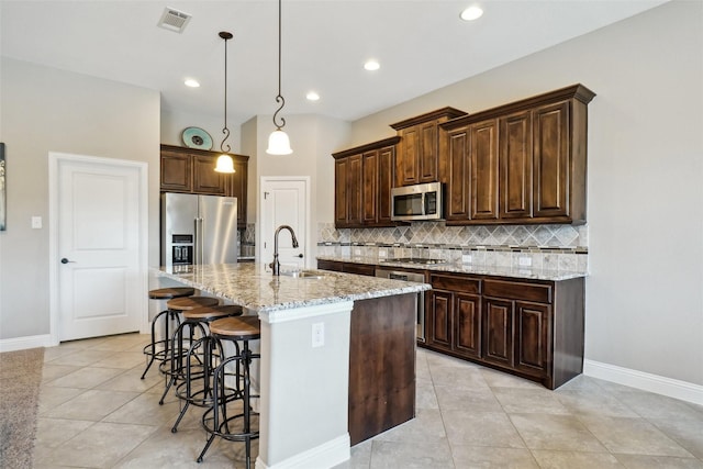 5009 Thistle Hl, Denton, TX 76210 - kitchen featuring appliances with stainless steel finishes, decorative backsplash, light tile patterned flooring, a breakfast bar, and recessed lighting