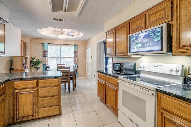 6824 Ridgewood Dr, North Richland Hills, TX 76182 - kitchen with white electric range oven, stainless steel microwave, brown cabinetry, dark countertops, and a textured ceiling
