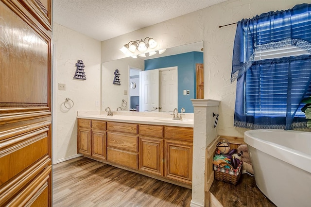 6824 Ridgewood Dr, North Richland Hills, TX 76182 - full bath with a textured wall, wood finished floors, double vanity, a textured ceiling, and a soaking tub