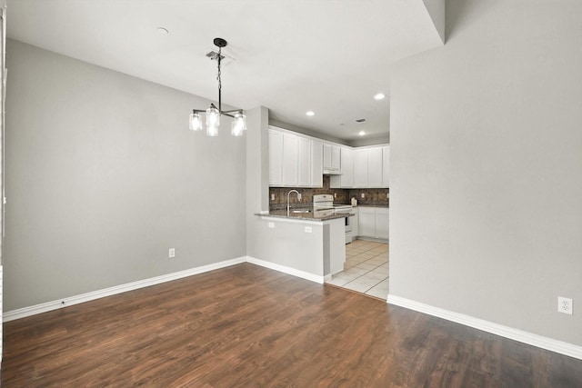 921 Englewood Ln, Plano, TX 75025 - kitchen with electric stove, a peninsula, white cabinetry, backsplash, and wood finished floors