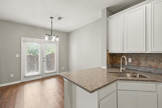 921 Englewood Ln, Plano, TX 75025 - kitchen with white cabinetry, wood finished floors, decorative backsplash, dark stone countertops, and decorative light fixtures