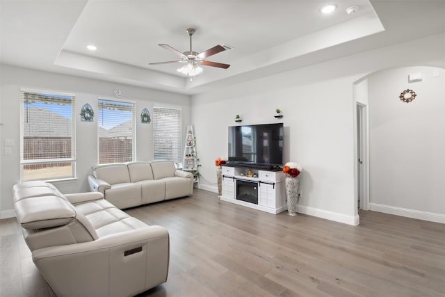 6205 Kent Ln, Celina, TX 76227 - living area featuring a raised ceiling, arched walkways, ceiling fan, light wood-style floors, and recessed lighting