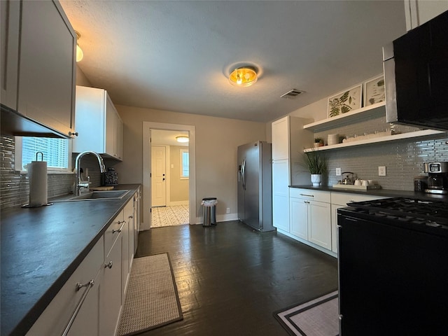 317 W Monterey St, Denison, TX 75020 - kitchen with stainless steel fridge, black gas stove, dark countertops, decorative backsplash, and white cabinets