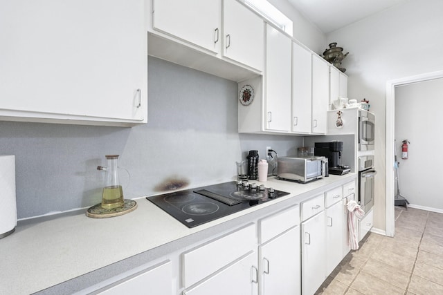4653 Portrait Ln, Plano, TX 75024 - kitchen with black electric stovetop, light countertops, white cabinets, light tile patterned floors, and stainless steel oven