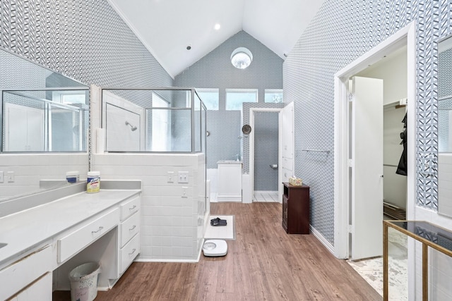 4653 Portrait Ln, Plano, TX 75024 - bathroom featuring wood finished floors, a tile shower, lofted ceiling, a spacious closet, and vanity
