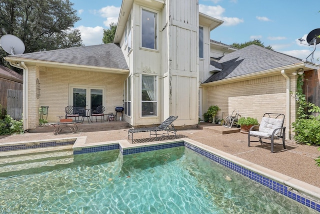 4653 Portrait Ln, Plano, TX 75024 - back of property featuring brick siding, roof with shingles, a patio area, and an outdoor pool
