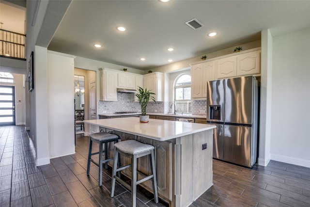 539 Curtiss Dr, Fate, TX 75087 - kitchen with appliances with stainless steel finishes, wood finish floors, a kitchen island, tasteful backsplash, and under cabinet range hood