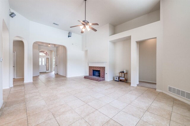 1809 N Holland Rd, Mansfield, TX 76063 - unfurnished living room featuring arched walkways, ceiling fan, light tile patterned floors, a high ceiling, and a fireplace