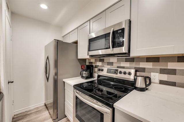 5750 Phoenix Dr Unit 39, Dallas, TX 75231 - kitchen featuring appliances with stainless steel finishes, light wood-type flooring, tasteful backsplash, white cabinets, and recessed lighting