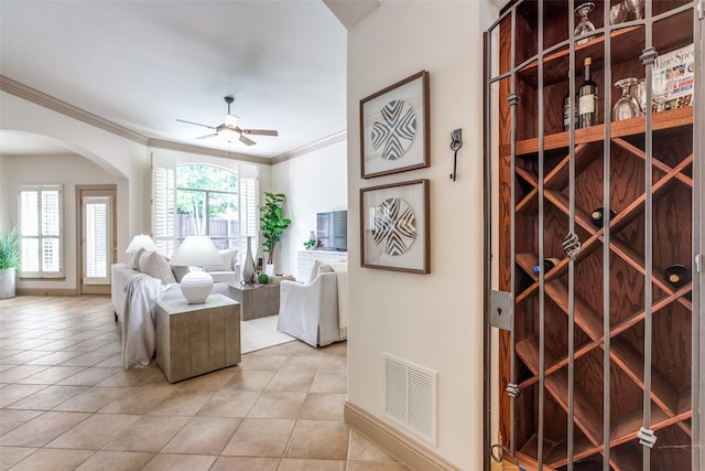 5701 Travis Dr, Frisco, TX 75034 - wine room featuring crown molding, a ceiling fan, arched walkways, and light tile patterned flooring