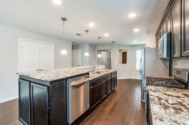 2111 Bentwater Ln, Frisco, TX 75036 - kitchen with appliances with stainless steel finishes, a center island with sink, dark wood-type flooring, light stone counters, and recessed lighting