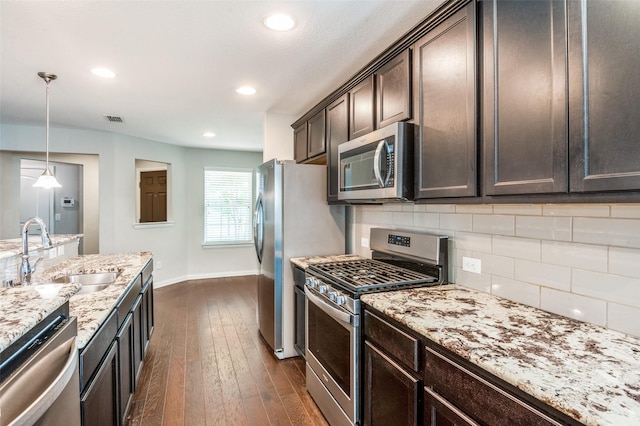 2111 Bentwater Ln, Frisco, TX 75036 - kitchen featuring stainless steel appliances, dark brown cabinets, decorative backsplash, light stone countertops, and dark wood-type flooring