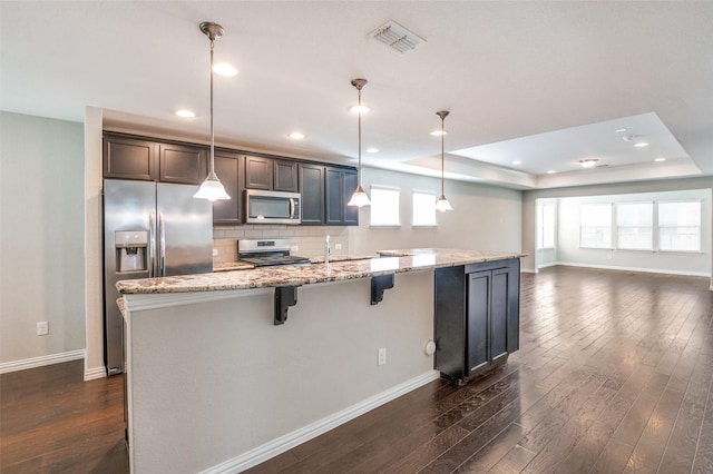 2111 Bentwater Ln, Frisco, TX 75036 - kitchen featuring stainless steel appliances, dark wood finished floors, open floor plan, a tray ceiling, and recessed lighting