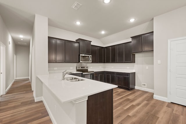 812 13th St, Plano, TX 75074 - kitchen featuring stainless steel appliances, wood finished floors, dark brown cabinetry, recessed lighting, and vaulted ceiling