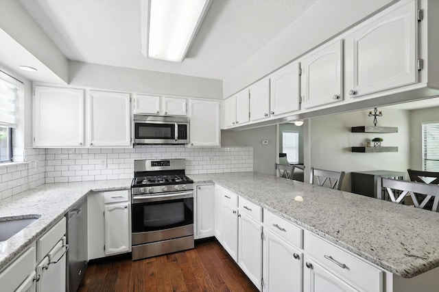 1227 Eaton Ln, Grapevine, TX 76051 - kitchen with stainless steel appliances, a peninsula, white cabinets, and backsplash