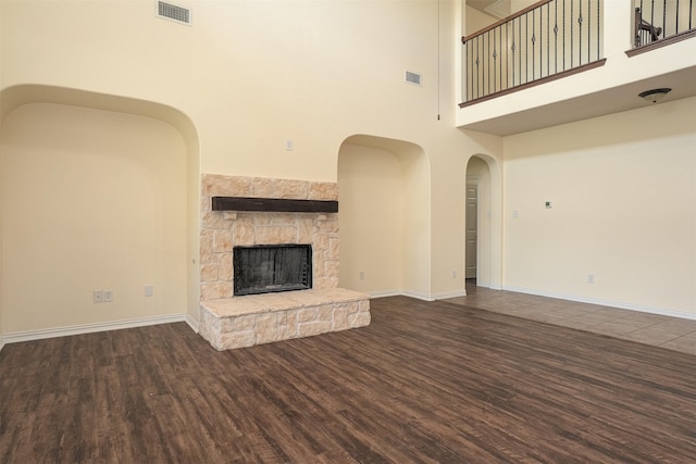 1220 Berkeley Dr, Burleson, TX 76028 - unfurnished living room featuring wood finished floors, a high ceiling, a fireplace, and arched walkways
