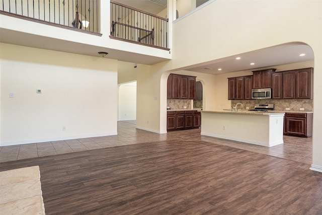 1220 Berkeley Dr, Burleson, TX 76028 - unfurnished living room featuring arched walkways, dark wood-style floors, a high ceiling, and recessed lighting