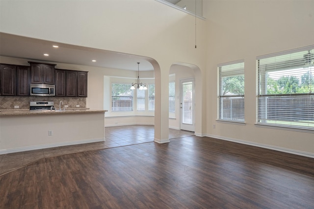 1220 Berkeley Dr, Burleson, TX 76028 - kitchen featuring stainless steel appliances, open floor plan, a chandelier, dark brown cabinets, and dark wood-type flooring