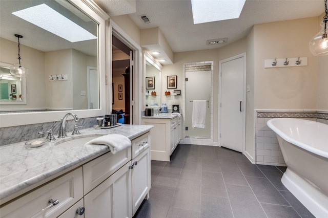 5205 Shady Springs Ct, Arlington, TX 76017 - bathroom with a skylight, two vanities, a freestanding tub, tile patterned floors, and a wainscoted wall