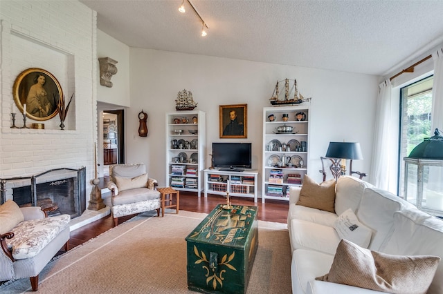 5205 Shady Springs Ct, Arlington, TX 76017 - living room featuring wood finished floors, a textured ceiling, a brick fireplace, lofted ceiling, and rail lighting