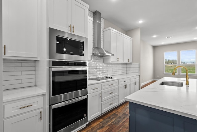 1955 Johnnie Dr, Springtown, TX 76082 - kitchen featuring appliances with stainless steel finishes, wall chimney exhaust hood, dark wood-type flooring, light stone counters, and white cabinetry