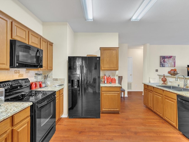 1928 Juniper Dr, Little Elm, TX 75068 - kitchen with black appliances, light wood-style flooring, decorative backsplash, and light stone countertops
