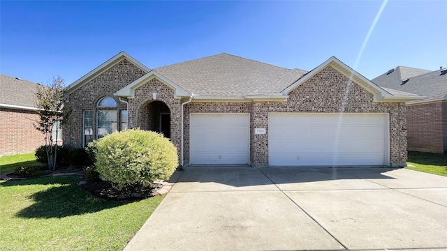 7811 Corona Ct, Arlington, TX 76002 - view of front of house featuring an attached garage, concrete driveway, a shingled roof, brick siding, and a front yard
