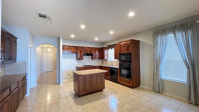 7811 Corona Ct, Arlington, TX 76002 - kitchen featuring black appliances, a center island, arched walkways, decorative backsplash, and under cabinet range hood