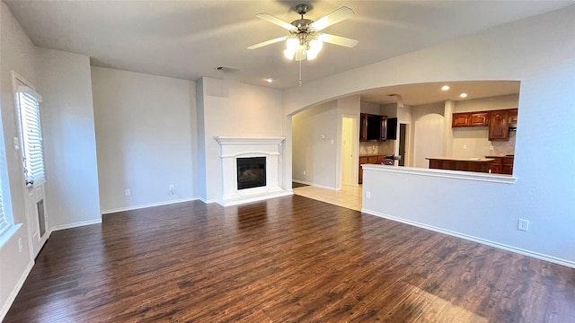 7811 Corona Ct, Arlington, TX 76002 - unfurnished living room with wood finished floors, a ceiling fan, arched walkways, a glass covered fireplace, and recessed lighting