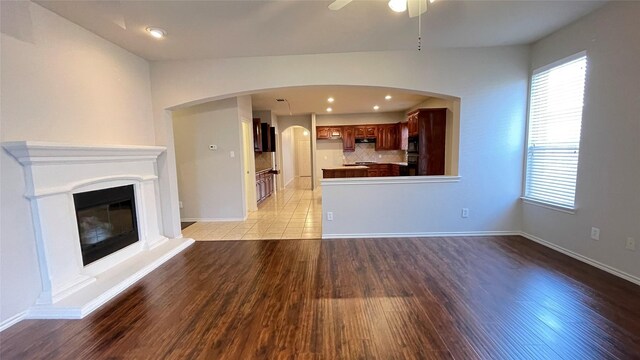 7811 Corona Ct, Arlington, TX 76002 - unfurnished living room featuring light wood-style flooring, a ceiling fan, a glass covered fireplace, and recessed lighting