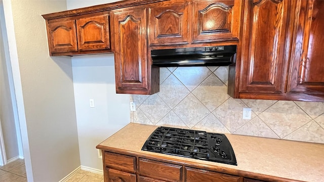 7811 Corona Ct, Arlington, TX 76002 - kitchen featuring black gas cooktop, under cabinet range hood, light countertops, backsplash, and light tile patterned floors